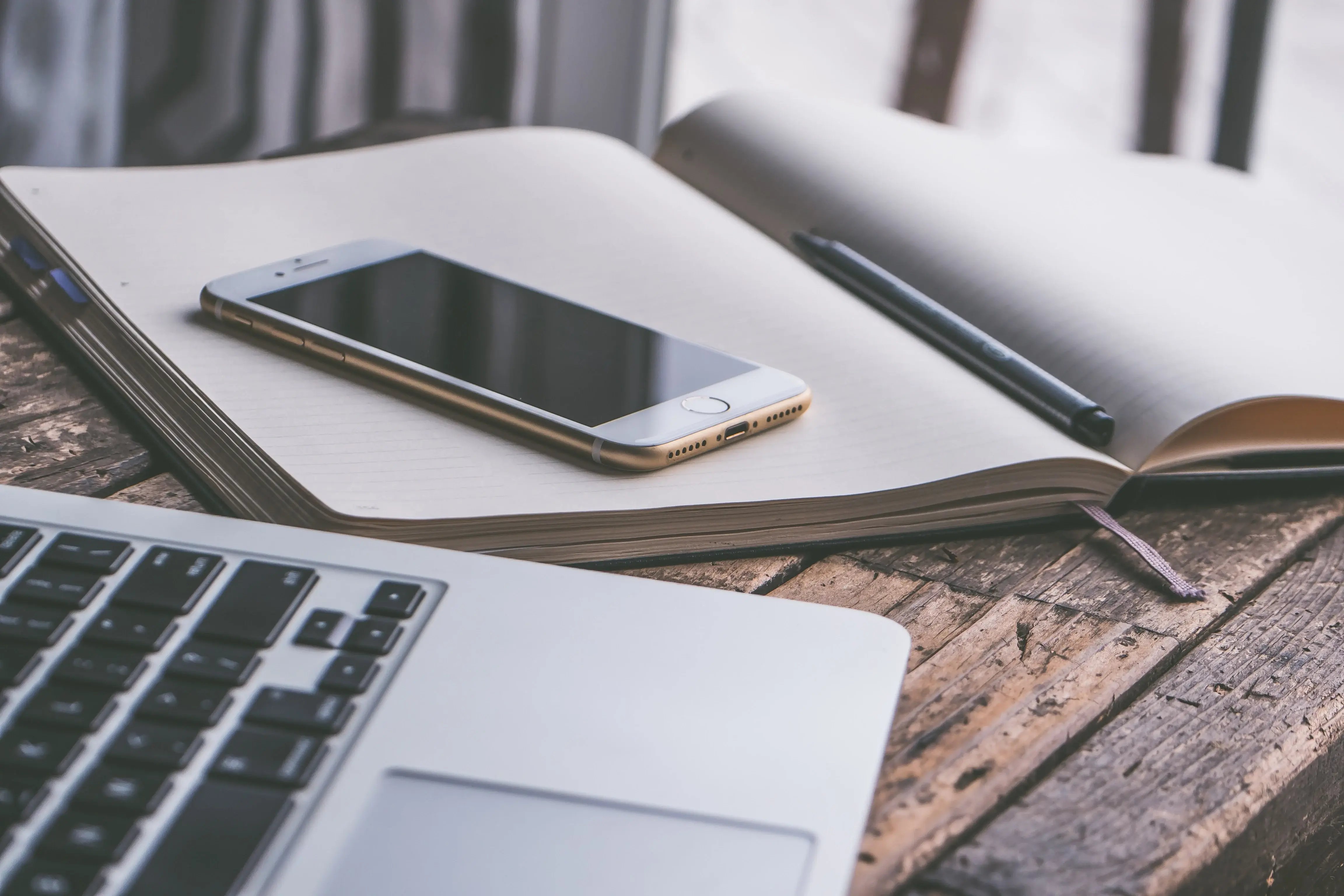 white iPhone on a notebook beside a laptop